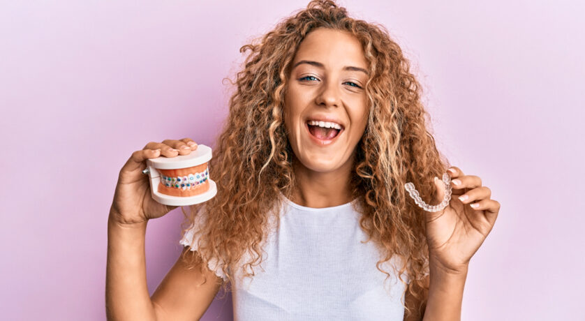 Woman smiling with Invisalign aligners in hand